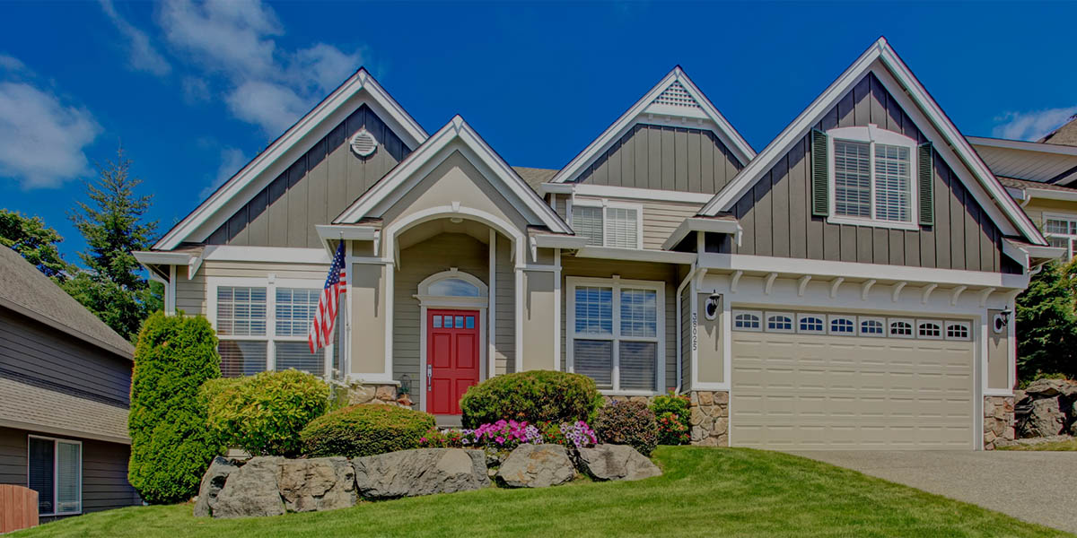 A suburban home with a multi-gabled roof, a bright red front door, and an American flag